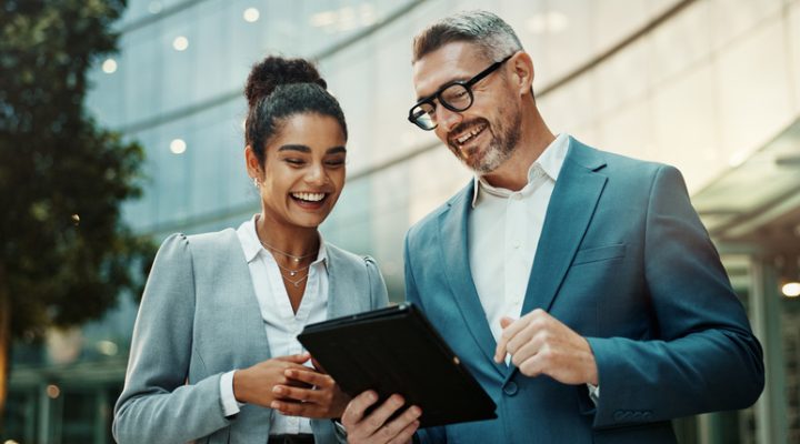 Man, woman and tablet for business in city with smile for approval, deal or notification from contact. People, partner and digital touchscreen with reading, happy and app for good news